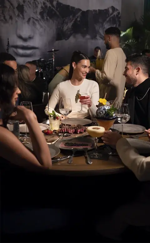Guests dining and talking at a table at Rosa Negra Miami